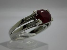 Contemporary 18ct white gold ring, set with a large ruby flanked by baguette-cut diamond