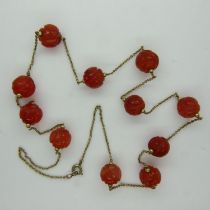 Unusual 19th century unmarked gold necklace, set with eleven carved carnelian beads, L: 63 cm. UK