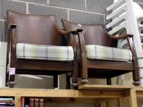 Pair of mid century wooden, leather bound arm chairs with light tartan cushions. Not available for