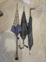 Three umbrellas including one with a carved wooden handle.