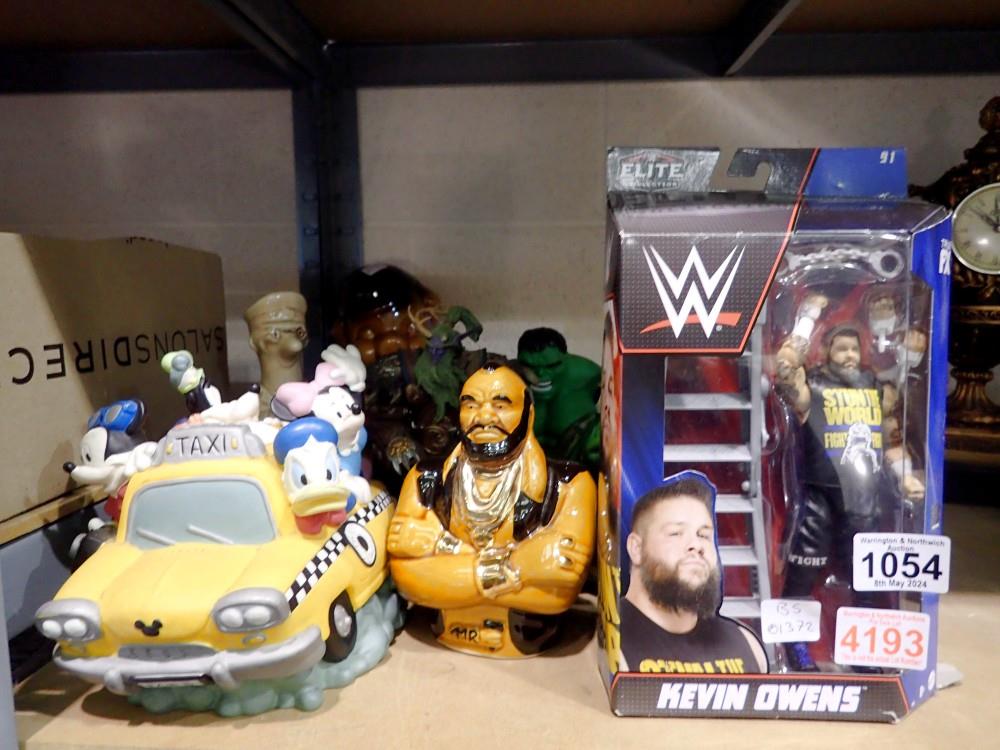 Selection of character money boxes and toys to include Kevin Owens, in box. Not available for in-