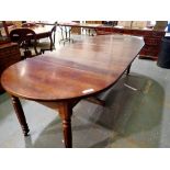 Circular walnut dining table on turned supports, with four additional leaves. Not available for in-