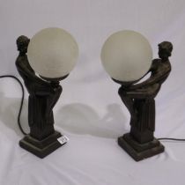 Pair of lady figurines on plinth holding globular bulbs, H: 44 cm. Not available for inhouse