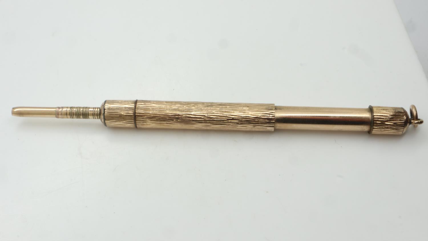 A yellow metal propelling pencil, bark-effect with jump-ring, extended L: 13 cm. UK P&P Group 1 (£