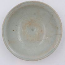 A celadon glazed porcelain bowl having incised decoration to its interior and a footed base, D: 17