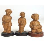 Three Chinese carved wooden figures of children, tallest 9.5cm high, on wooden bases with a hardwood