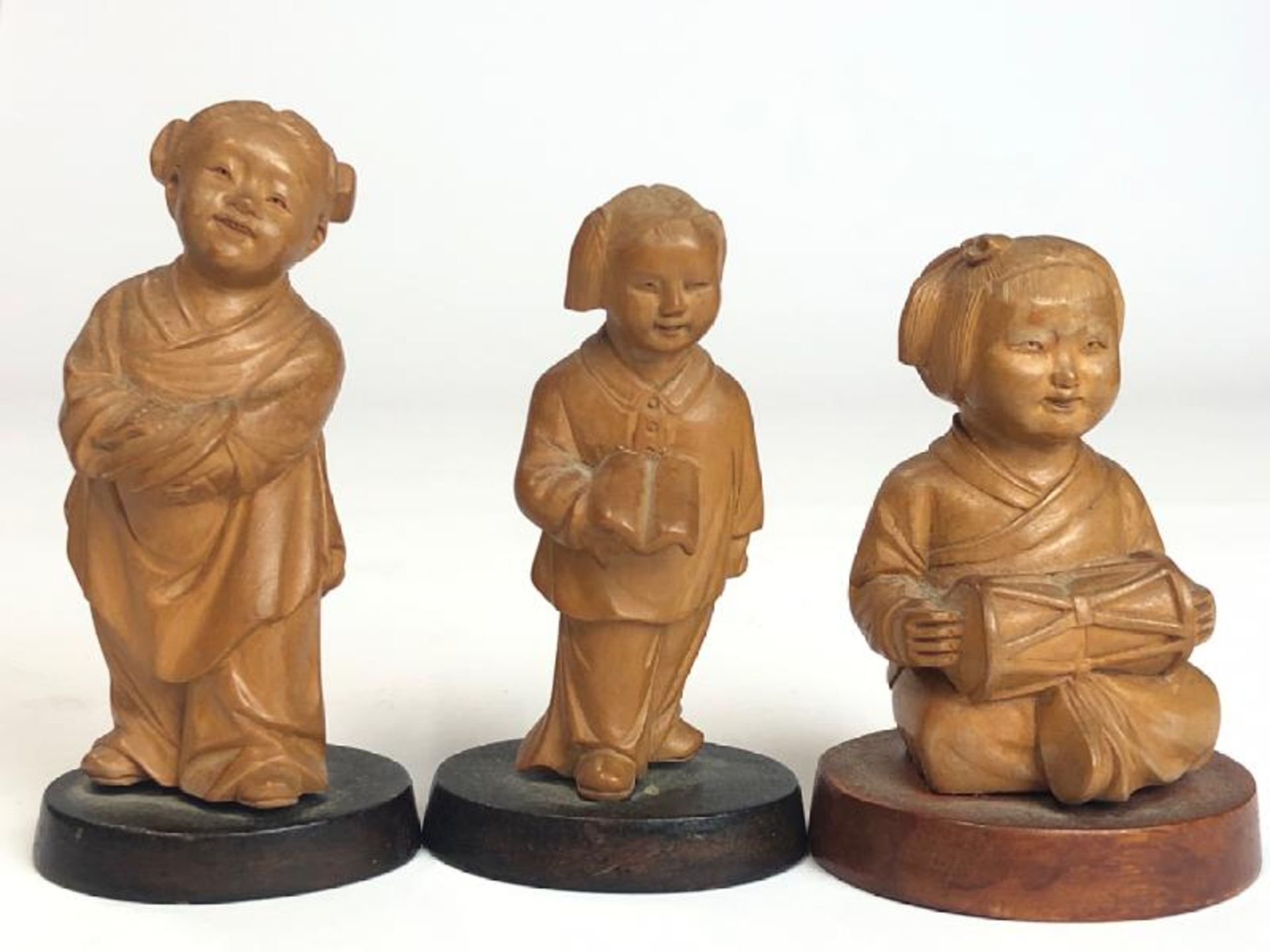 Three Chinese carved wooden figures of children, tallest 9.5cm high, on wooden bases with a hardwood