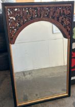 A carved and painted gilt Chinese mirror, with oriental figures in a relief arch at top, 65 x