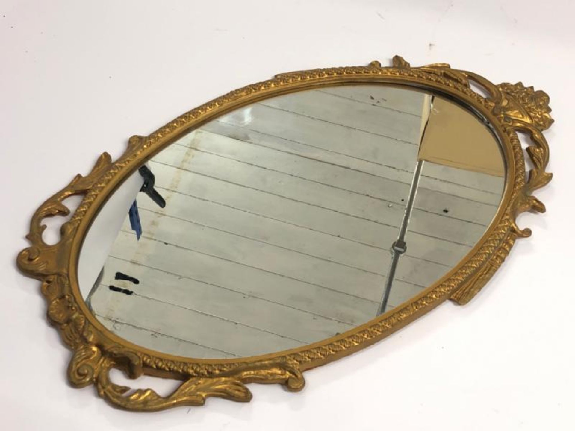 A small oval wall mirror with decorative metal frame, 48cm high