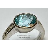An aquamarine and diamond ring in hallmarked 18ct gold. The checquer board cut oval aquamarine