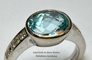 An aquamarine and diamond ring in hallmarked 18ct gold. The checquer board cut oval aquamarine