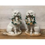 A pair of German porcelain Poodle dogs with baskets containing piglets, 19cm high / AN8