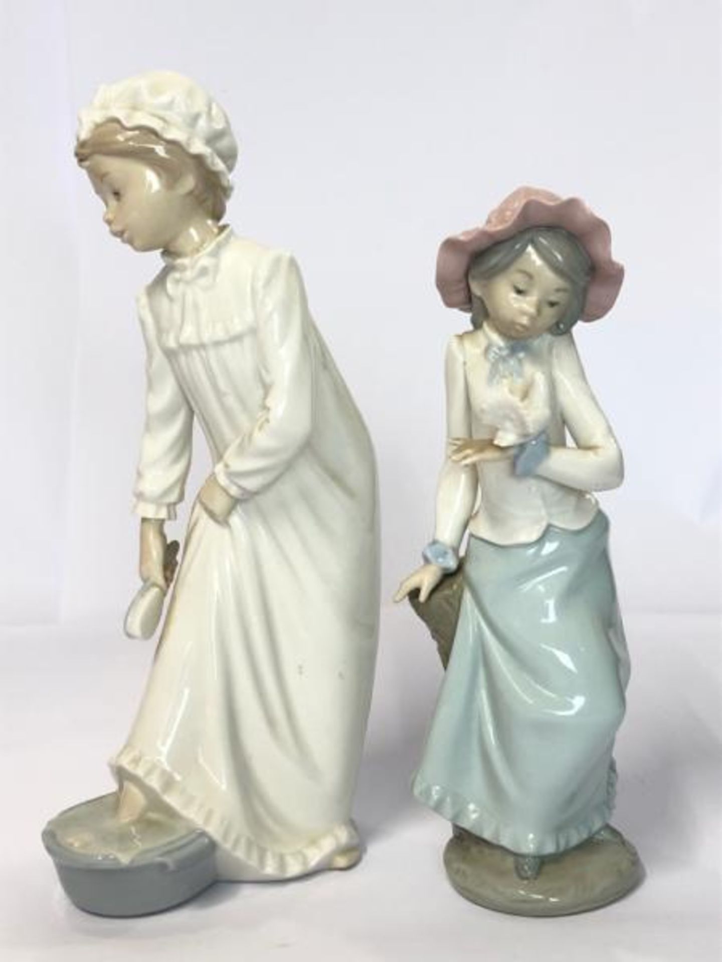 Two Lladro Nao figurines "Girl Takes a Footbath" and "Girl Holding Dove", tallest 28cm high / AN7