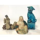 Three figurines, blue glazed Chinese foo dog, 16cm high, laughing Budha, 9cm high and flute