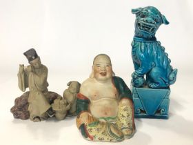 Three figurines, blue glazed Chinese foo dog, 16cm high, laughing Budha, 9cm high and flute