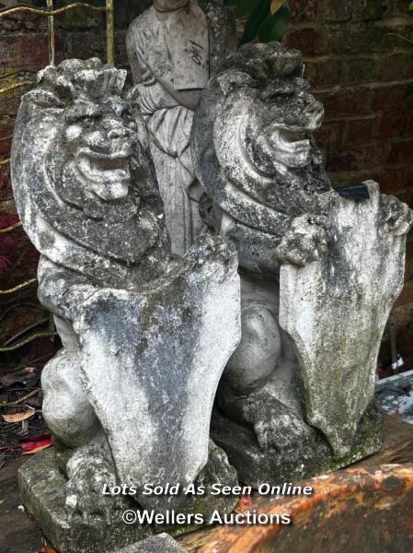 PAIR OF WEATHERED RE-CONSTITUTED STONE LIONS WITH SHIELDS, SOME WARE AND MINOR DAMAGE, THIS LOT IS