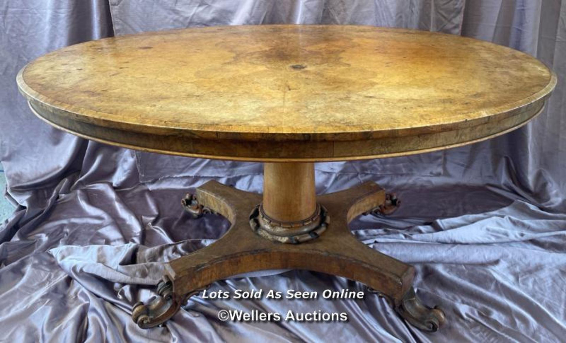 OVAL WALNUT CENTRE TABLE ON SOLID COLUMN BASE WITH FOUR DECORATIVE LEGS AND CASTORED FEET (IN NEED