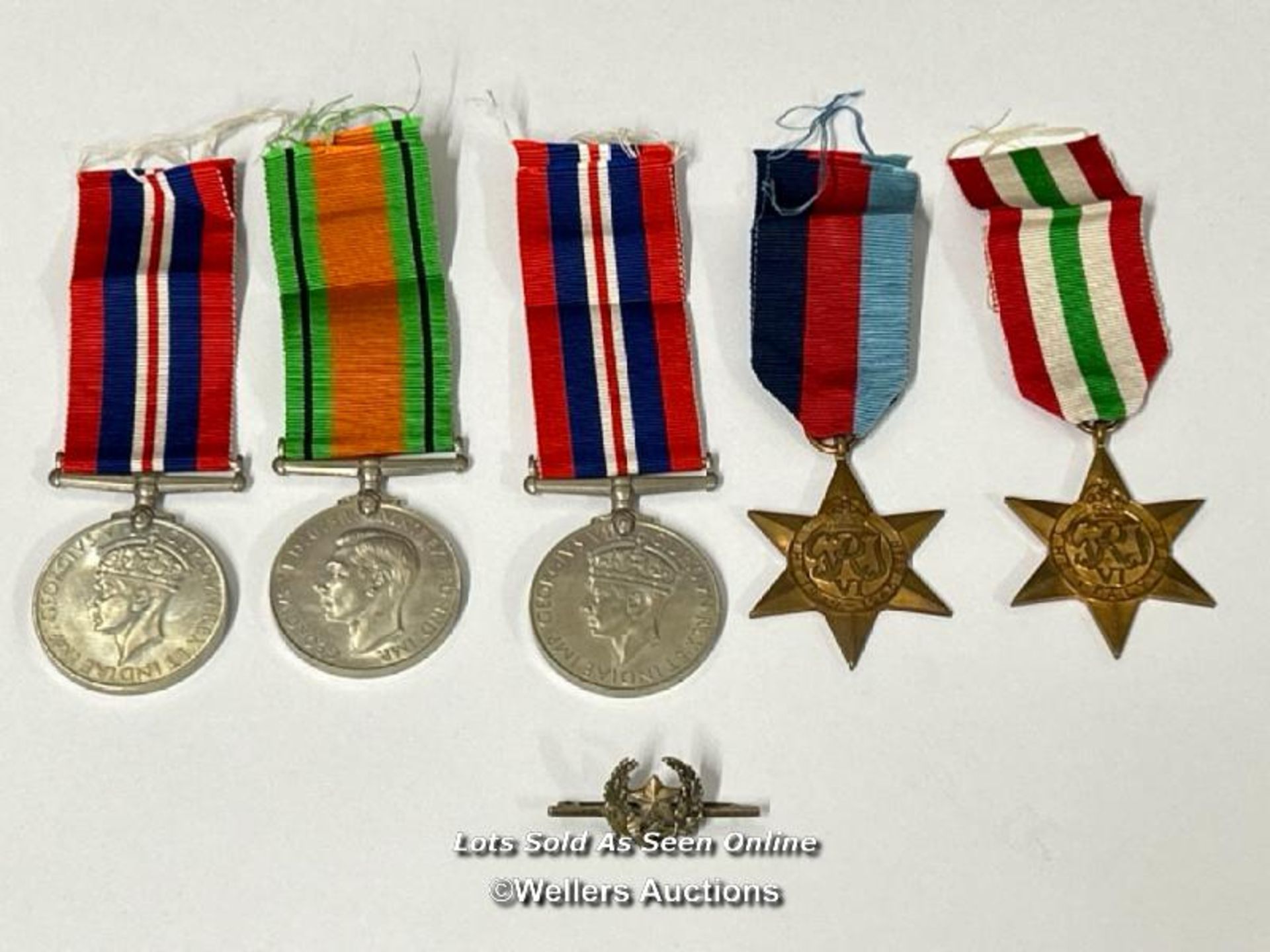 Four medals including the Italy star and the 1939-1945 star with a military cap badge stamped Silver