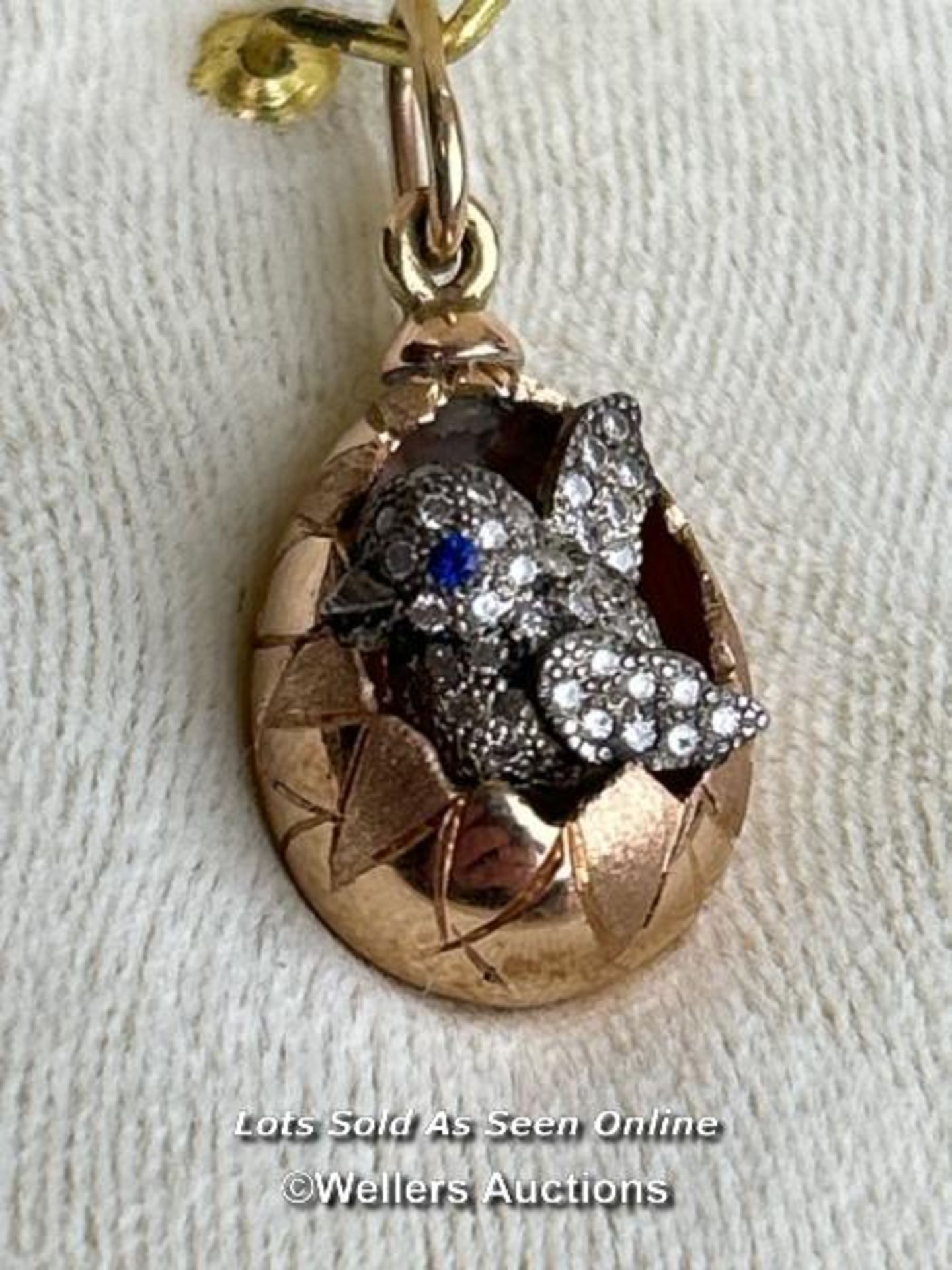 A Faberge style egg pendant with hatching diamond encrusted chick, measuring 20mm x 12mm, the loop