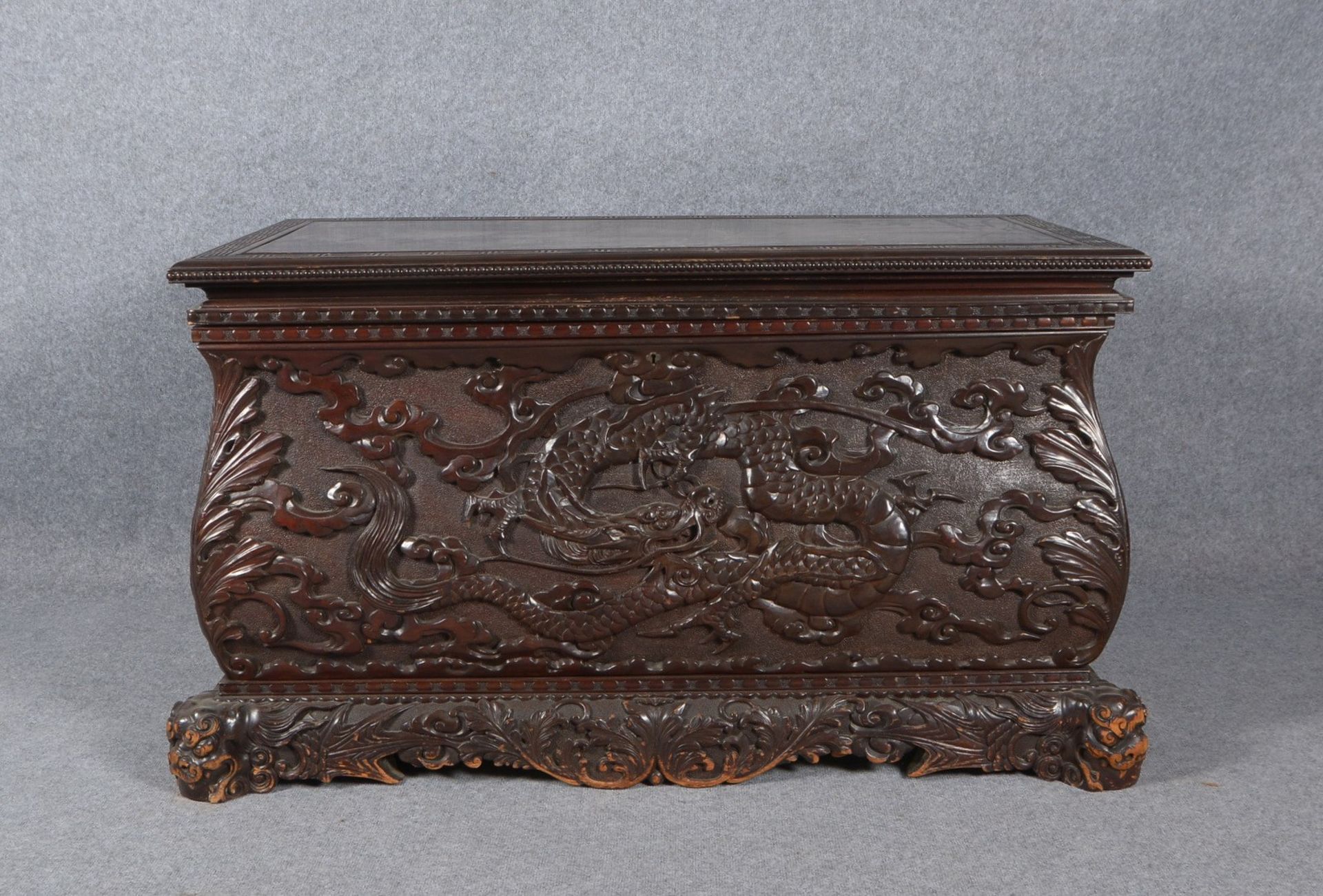 Holztruhe, mit geschnitztem Reliefdekor (Drachenmotiv), auf figürl. Füßen ('Fu-Hunde')