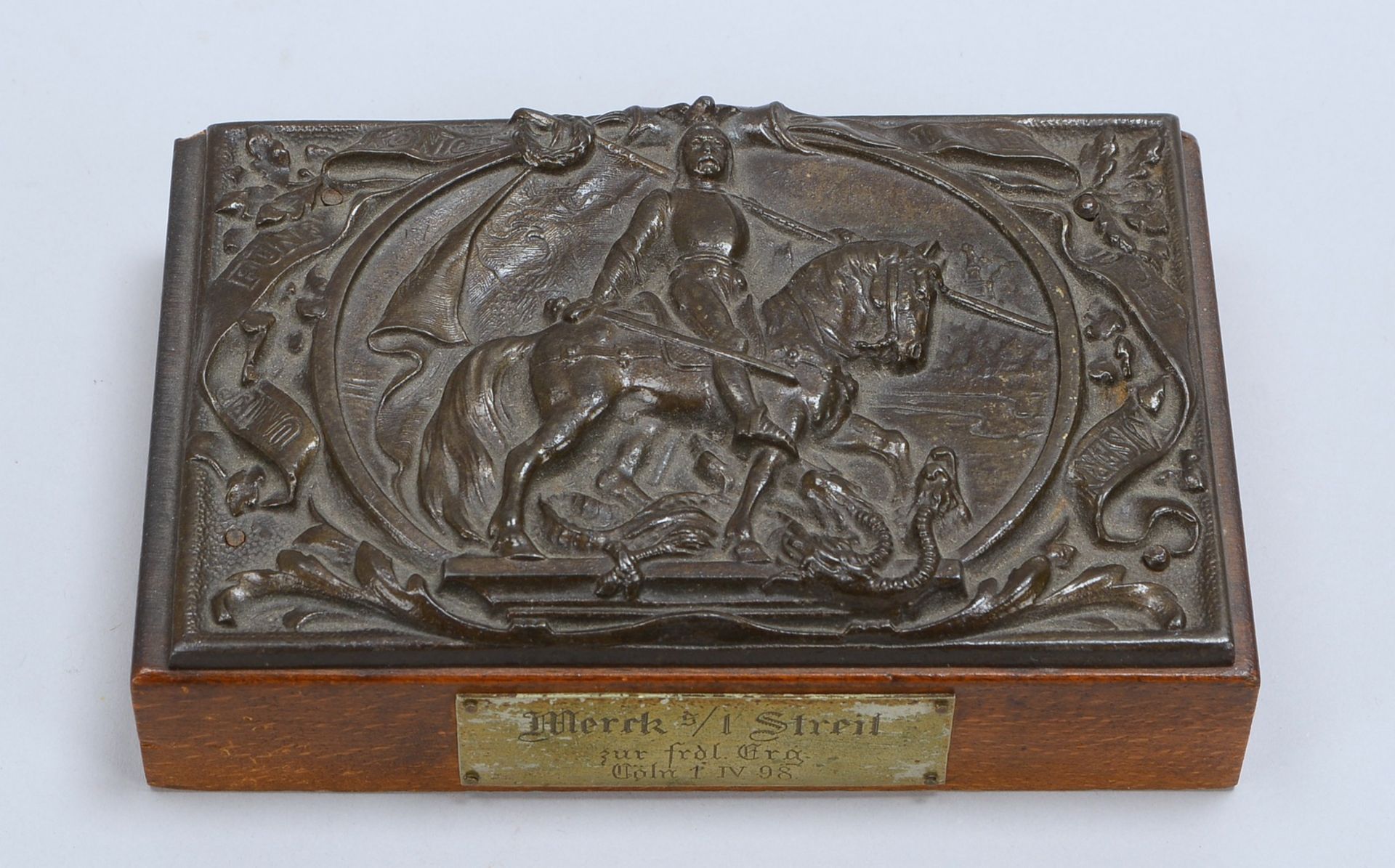 Briefbeschwerer (Ende 19. Jh.), Metall, relief. Motiv ('Drachentöter'), auf Holzplatte