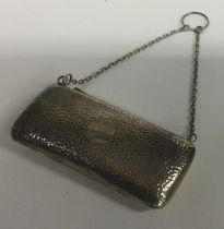 A silver purse of hammered design on suspension chain.