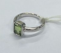 A 9 carat single stone ring with central green stone.