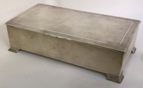 A large silver cigar box on feet with engine turned decoration.