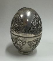 A Chinese silver box in the form of an egg with hinged top and pierced decoration.
