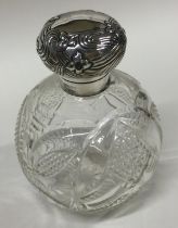 A silver and glass scent bottle with hinged top and chased decoration.