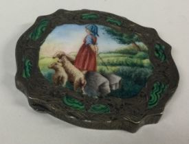 A large silver and enamelled compact depicting a scene of a girl with lambs.