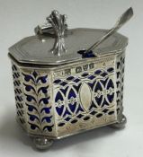 CHESTER: A pierced silver and glass mustard pot together with a spoon.