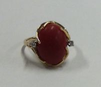 A small diamond and coral three stone cocktail ring in 14 carat gold mount.