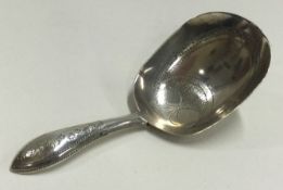 A Georgian silver caddy spoon with bright cut decoration. Maker's mark only.
