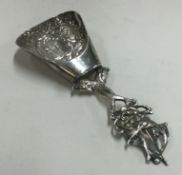 A Continental silver chased caddy spoon.