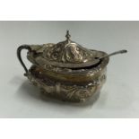 A chased silver and glass mustard pot. Sheffield 1909.