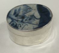 A Chinese silver box bearing import marks with porcelain top.