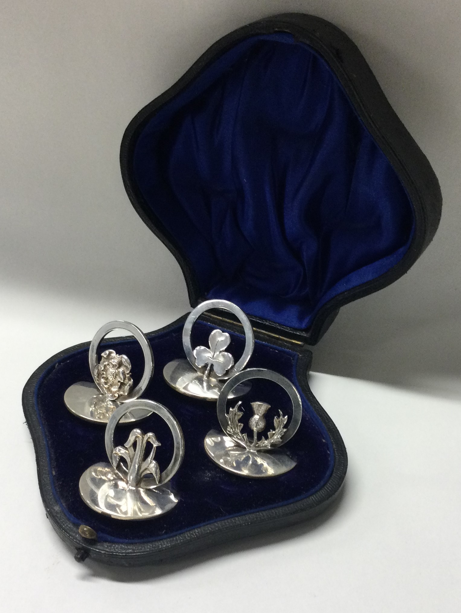 A set of four silver menu holders depicting thistles and flowers.
