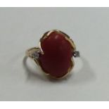 A small diamond and coral three stone cocktail ring in 14 carat gold mount.