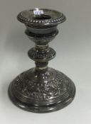 A heavy silver candle holder with embossed decoration.