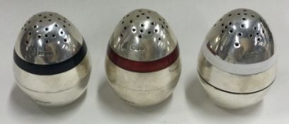 A suite of three silver and enamelled peppers. London 1920.