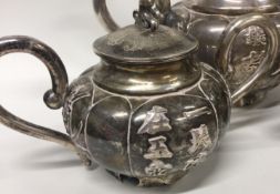 A Chinese export silver three piece teaset decorated with oriental script and bamboo.