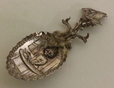 A heavy Continental silver embossed caddy spoon cast with serpents and ship.