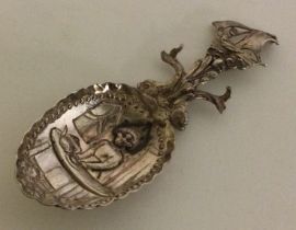 A heavy Continental silver embossed caddy spoon cast with serpents and ship.