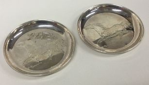 A pair of silver dishes engraved with horses. Signed to base.