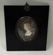 An oval portrait of a lady in a rectangular frame.