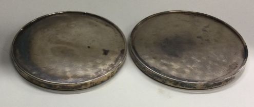 A pair of circular silver coasters.