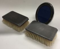 A small pair of engine turned silver brushes together with a picture frame.