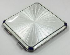 A silver and white enamelled compact with blue corners.