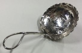 A large chased silver caddy spoon bearing import marks.